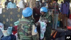 FILE - U.N. peacekeeper soldiers hold a baby as South Sudanese people seek protection at the U.N. camp in Juba, South Sudan, July 14, 2016.