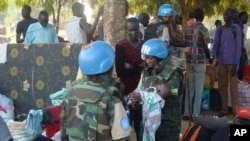 FILE - In this photo taken July 14, 2016 and released by the United Nations Mission in South Sudan (UNMISS), UN peacekeeper soldiers hold a baby as South Sudanese people seek protection at the UN camp in Juba, South Sudan.