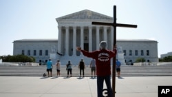 Tom Alexander holds a cross as he prays prior to rulings outside the Supreme Court on Capitol Hill in Washington, July 8, 2020.