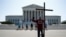 Tom Alexander holds a cross as he prays prior to rulings outside the Supreme Court on Capitol Hill in Washington, July 8, 2020.