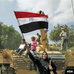 Yon dam egypsyèn ak yon drapo peyi li ka p selebre devan yon tank lame egypsyen an sou plas Tahrir la, nan Lekèr. AP. 02/12/2011