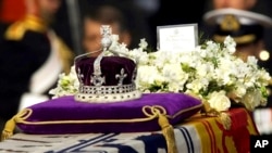 FILE - The Koh-i-noor, or "mountain of light," diamond, set in the Maltese Cross at the front of the crown made for Britain's late Queen Mother Elizabeth, is seen on her coffin, along with her personal standard, a wreath and a note from her daughter, Quee