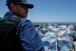 Seorang agen penjaga pantai AS mengawasi lebih dari 13 ton kokain yang disita di lepas pantai Meksiko dan Amerika Selatan Tengah sebelum diturunkan dari Coast Guard Cutter Steadfast di pelabuhan di San Diego, California, AS, 26 Juli 2019. (Foto: REUTERS)