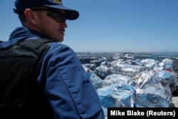 Seorang agen penjaga pantai AS mengawasi lebih dari 13 ton kokain yang disita di lepas pantai Meksiko dan Amerika Selatan Tengah sebelum diturunkan dari Coast Guard Cutter Steadfast di pelabuhan di San Diego, California, AS, 26 Juli 2019. (Foto: REUTERS)