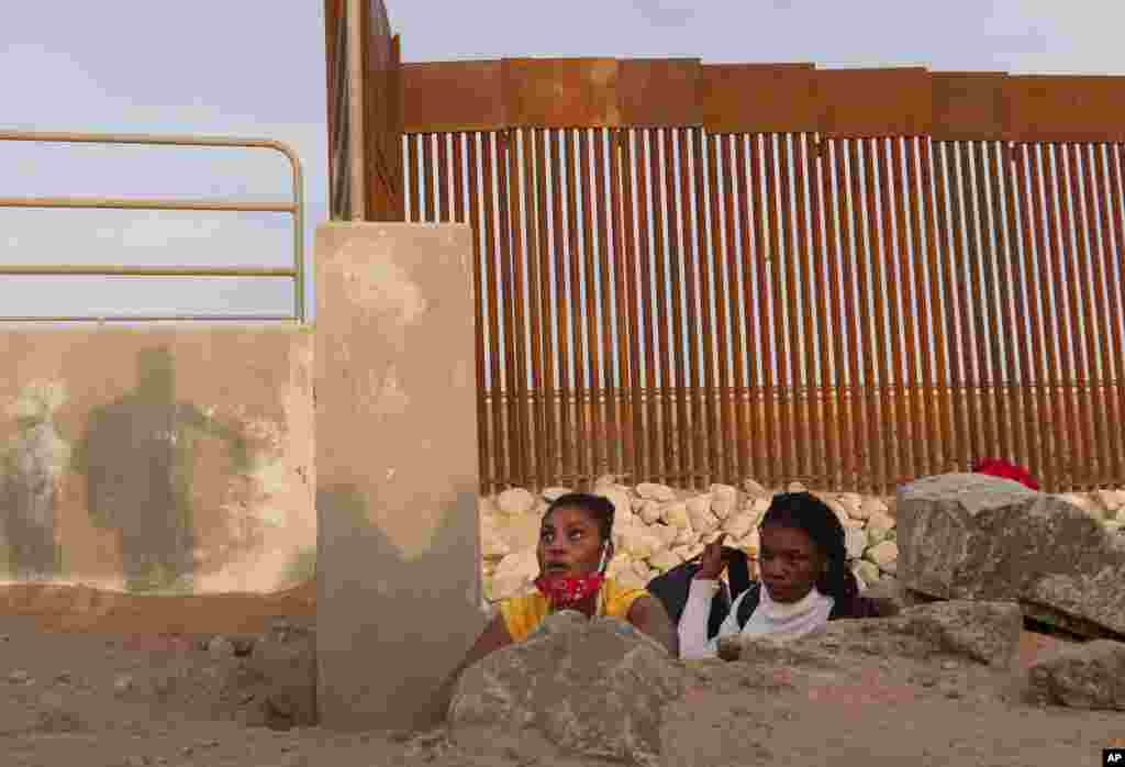 A Haitian migrant family looks to emerge from a rocky canal adjacent to a gap in the U.S. border wall in Yuma, Arizona, June 9, 2021.