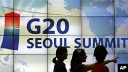Women walk by a screen showing a G20 Seoul Summit sign at the venue for the upcoming summit meeting, scheduled November 11-12 in Seoul, South Korea, 02 Nov 2010