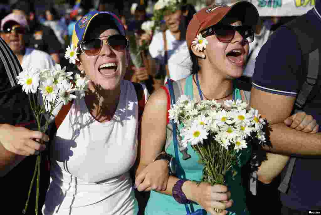 Supporters of opposition leader Leopoldo Lopez hold flowers and shout during a rally to promote peace in Caracas, Feb. 20, 2014. 