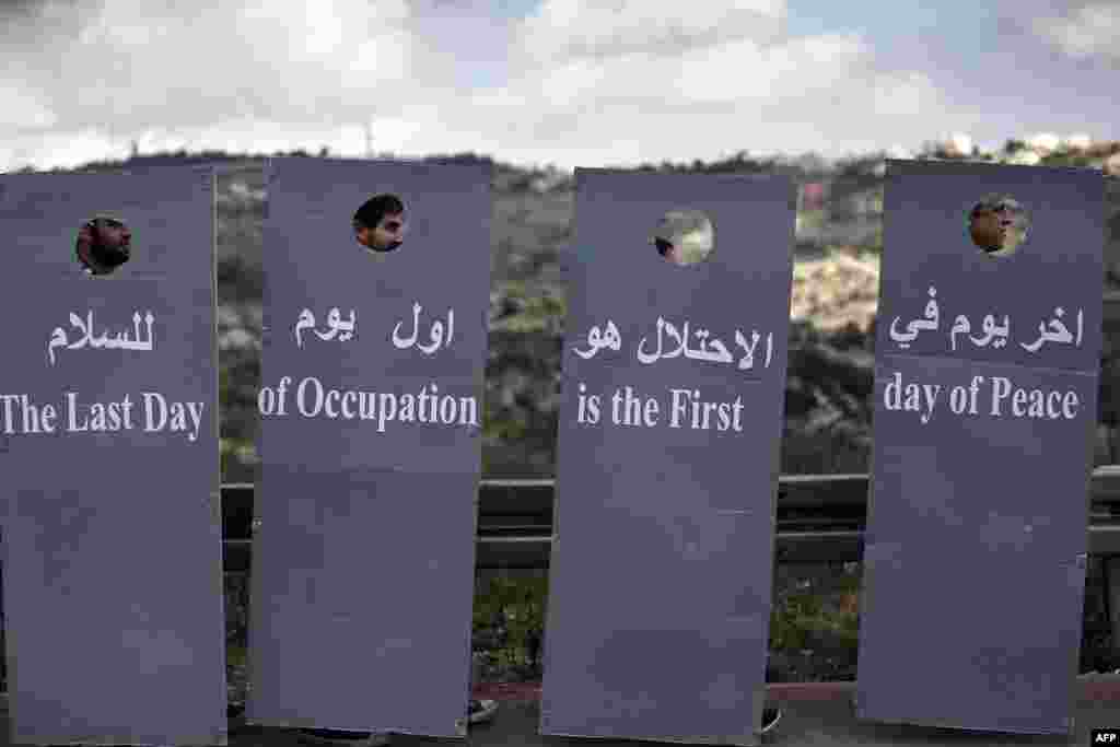 Những nhà hoạt động vì hòa bình người Israel và Palestine đi sau những tấm bìa các-tông thể hiện hình ảnh rào cản ngăn cách gây tranh cãi của Israel trong một cuộc tuần hành vì hòa bình tại một con đường của Israel, gần một chốt kiểm soát giữa thành phố Beit Jala thuộc Bờ Tây và Jerusalem.