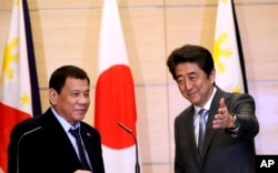 Philippine President Rodrigo Duterte, left, is shown the way by Japanese Prime Minister Shinzo Abe after a joint press conference following their meeting at Abe's official residence in Tokyo, Oct. 26, 2016.