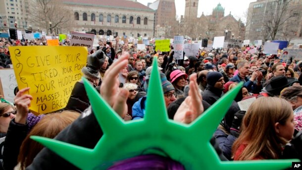 En Boston, un manifestante lleva un sombrero de la Estatua de la Libertad y aplaude durante una manifestación celebrada en protesta contra la orden del presidente Donald Trump que restringe el viajes a los Estados Unidos.
