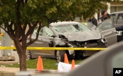 Police investigate a damaged car after the vehicle crashed into a crowd of spectators during the Oklahoma State University homecoming parade, causing multiple injuries and deaths, in Stillwater, Okla., Oct. 24, 2015.