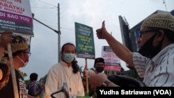 Perwakilan Orang Muda Katolik, Pandu (baju putih berkalung salib) membagikan takjil pada warga muslim di Solo Baru, Jalur perbatasan kota Solo dan Kabupaten Sukoharjo, Jumat (7/5). (Foto : VOA/ Yudha Satriawan)