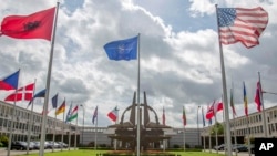 FILE - Flags of member nations flap in the wind outside NATO headquarters in Brussels, Aug. 29, 2014. 