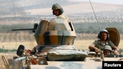 Turkish soldiers on an armored personnel carrier escort a military convoy on a road in Karkamis on the Turkish-Syrian border in Turkey's southeastern Gaziantep province, Aug. 26, 2016.