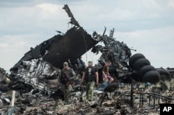 Pro-Russian fighters collect ammunition from the site of remnants of a downed Ukrainian army aircraft Il-76 at the airport near Luhansk, Ukraine, June 14, 2014.