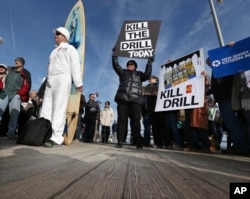 FILE - Scott Thompson, left, leans against his surfboard as he joins a gathering at a rally in Asbury Park, N.Y., to oppose federal plans that would allow oil and gas drilling in the Atlantic Ocean, Jan. 31, 2016. President Barack Obama has now designated the bulk of U.S.-owned waters in the Arctic Ocean and certain areas in the Atlantic Ocean as indefinitely off limits to future oil and gas leasing.