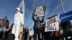 Scott Thompson, left, leans against his surfboard as he joins a gathering at a rally in Asbury Park, N.Y., to oppose federal plans that would allow oil and gas drilling in the Atlantic Ocean, Jan. 31, 2016. President Barack Obama has now designated the bu