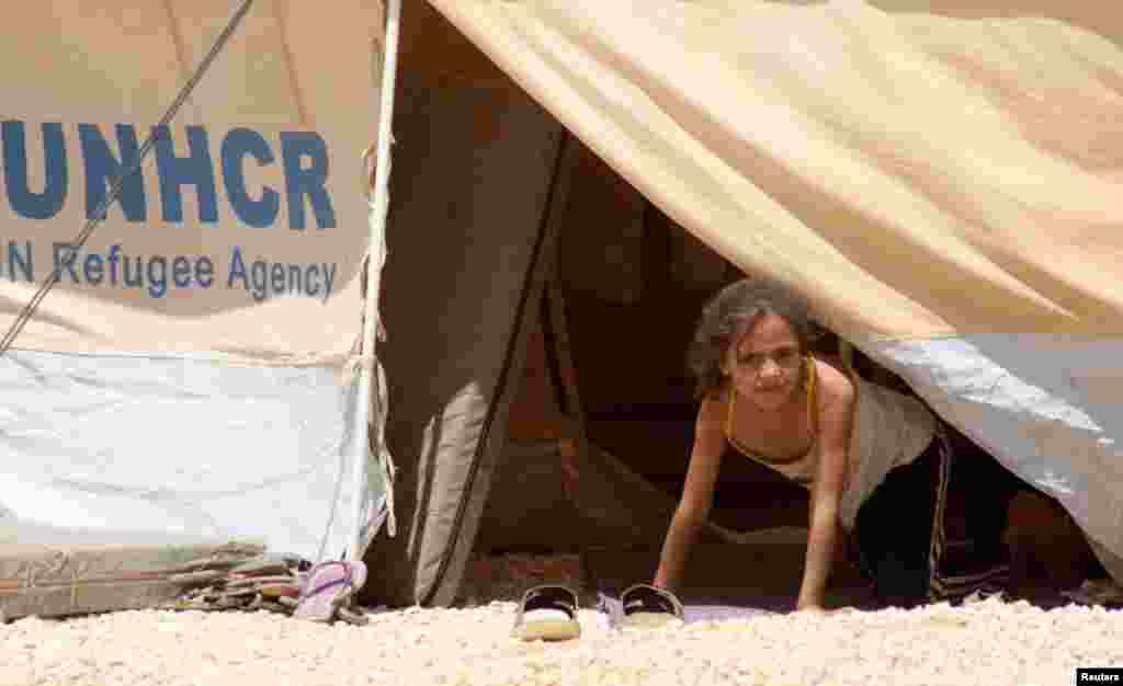 Gadis kecil pengungsi dari Suriahmelongok dari tenda berdebu di kamp pengungsi Al Zaatri di Mafraq, Yordania, dekat perbatasan dengan Suriah (13/8).