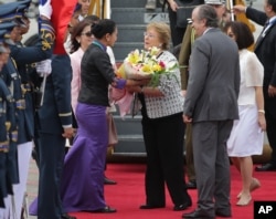 ປະທານາທິບໍດີ ຊີເລ ທ່ານນາງ Michelle Bachelet (ກາງຂວາ) ຮັບເອົາຊໍ້ດອງໄມ້ ຂະນະທີ່ເດີນທາງໄປເຖິງ ສະໜາມບິນສາກົນ ຂອງນະຄອນ ມານີລາ ປະເທດຟີລິບປິນ ເພື່ອຂົ້າຮ່ວມກອງປະຊຸມສຸດຍອດ ດ້ານການຮ່ວມມື ເສດຖະກິດ ເອເຊຍ-ປາຊີຟິກ ຫຼື Asia Pacific Economic Cooperation (APEC), ວັນທີ 15 ພະຈິກ 2015.