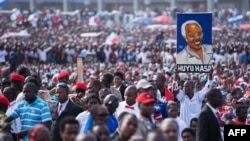 A man holds up a painted portrait of Edward Lowassa, former prime minister of Tanzania and presidential candidate for UKAWA, a coalition of four main opposition parties, during a political rally in Dar es Salaam, Tanzania, Aug. 29, 2015.