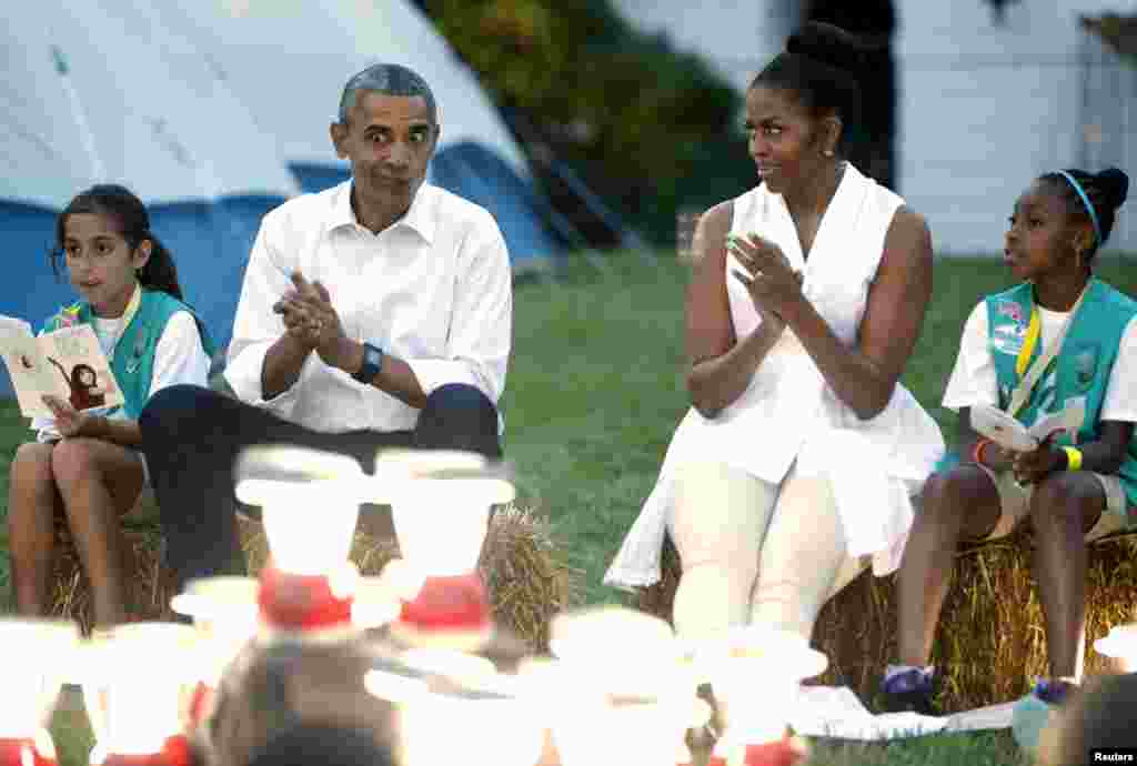 Presiden AS Barack Obama membuat ekpresi wajah yang konyol ketika ia dan ibu negara Michelle Obama bernyanyi bersama anak perempuan pramuka di halaman bagian selatan Gedung Putih di Washington 30 Juni 2015. 50 anak perempuan pramuka kelas empat berencana berkemah dan menginap di halaman tersebut, untuk merayakan seratus tahun gerakan pramuka dan Dinas Taman Nasional.