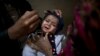 A Pakistani health worker, right, gives a polio vaccine to a child held by her mother at their home in Rawalpindi, Jan. 20, 2014.