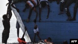 Les migrants tentent de tirer un enfant hors de l'eau en attendant d'être secourus par les membres de l'ONG Proactiva Open Arms dans la mer Méditerranée, à environ 12 miles nautiques au nord de la Libye, le 4 octobre 2016.