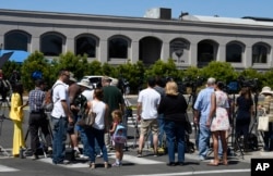 Neighbors and media members gather outside the Chabad of Poway synagogue, April 27, 2019, in Poway, Calif., after a shooting inside that resulted in at least one death.