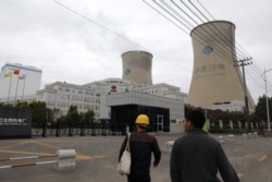 People walk past a China Energy coal-fired power plant in Shenyang, Liaoning province, China