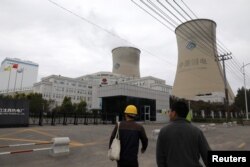 People walk past a China Energy coal-fired power plant in Shenyang, Liaoning province, China