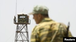 FILE - A frontier guard stands on a bridge to Afghanistan across Panj river in Panji Poyon border outpost, south of Dushanbe, Tajikistan, May 31, 2008. 