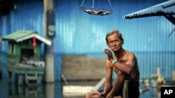 A man smokes a cigarette outside his flooded home in a slum just outside Bangkok, Thailand, November 21, 2011.