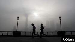 FILE - People jog past the Pudong Financial District shrouded with fog and pollution at the Shanghai Bund in Shanghai, China, April 14, 2016. 