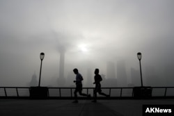 Beberapa orang sedang lari pagi melewati Pudong Financial District yang diselimuti kabut dan polusi di Shanghai, China, 14 April 2016. (Foto:Dok)