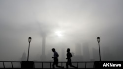 People jog past the Pudong Financial District shrouded with fog and pollution at the Shanghai Bund in Shanghai, China, Thursday, April 14, 2016. 