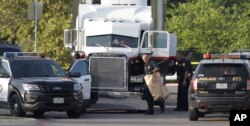 FILE - San Antonio police officers investigate the scene where eight people were found dead in a tractor-trailer loaded with at least 30 others outside a Walmart store in stifling summer heat in what police are calling a horrific human trafficking case, July 23, 2017.