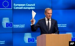 European Council President Donald Tusk holds up the Article 50 document from the UK during a media conference at the Europa building in Brussels, March 29, 2017.