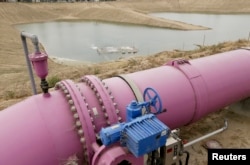 A purple pipe feeds recycled wastewater to a holding pond to recharge an underground aquifer at the Orange County Water District recharge facility in Anaheim, Calif, May 8, 2015.