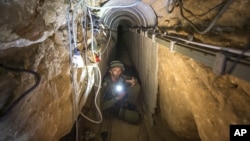 FILE - An Israeli army officer shows journalists a tunnel allegedly used by Palestinian militants for cross-border attacks from Gaza into Israel, July 25, 2014.