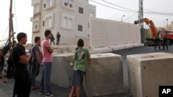 Warga Palestina mengamati tembok pemisah yang dibangun Israel untuk memisahkan permukiman warga Yahudi dan warga Muslim di Yerusalem timur, Minggu (18/10). 