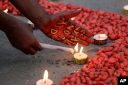 Orang-orang menyalakan lilin membentuk pita merah, simbol kesadaran dan dukungan universal bagi mereka yang hidup dengan HIV, pada Hari AIDS Sedunia di Kolkata, India, Rabu, 1 Desember 2021. (Foto: AP/Bikas Das)