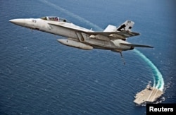 An F/A-18F Super Hornet jet flies over the USS Gerald R. Ford as the U.S. Navy aircraft carrier tests its EMALS magnetic launching system, which replaces the steam catapult, and new AAG arrested landing system in the Atlantic Ocean July 28, 2017. Picture