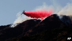 灭火飞机在加州阿祖萨一处野火现场附近向一座山坡喷洒阻燃剂。（2016年6月20日）