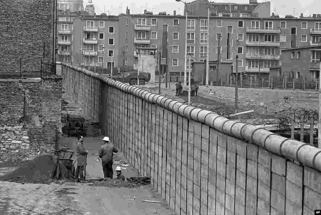 West German construction workers have a chat in West Berlin, April 18, 1967 at the meters high wall separating the city, as the communists hold their seventh party congress in East Berlin. (AP Photo/Edwin Reichert)