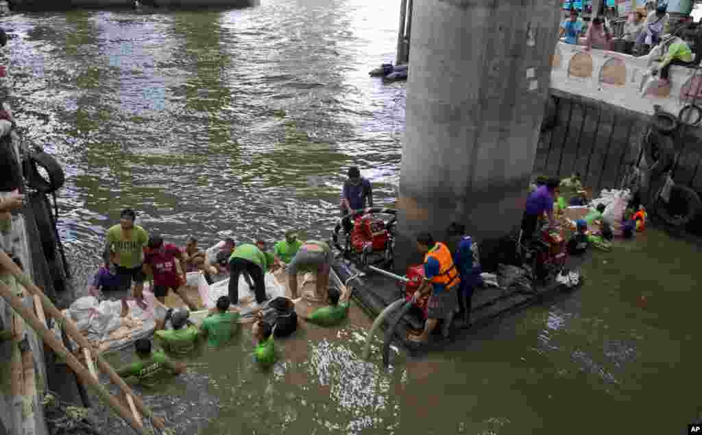 Trabalhadores constroem um dique com sacos de areia na tentativa de fechar o canal para melhor procurarem vestígios de explosivo que foi atirado ao canal na Terça-feira, em Banguecoque, Tailândia. Agosto 19, 2015.