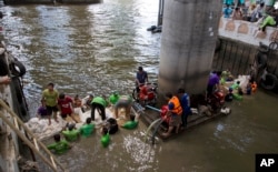Workers build a dam from sandbags as they attempt to seal off a canal to search for remnants of an explosive device that was thrown into the canal on Tuesday in Bangkok,Thailand, Aug. 19, 2015.