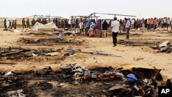 Refugees gather near burnt tents at Choucha camp in Tunisia near the Libyan border, May 22, 2011