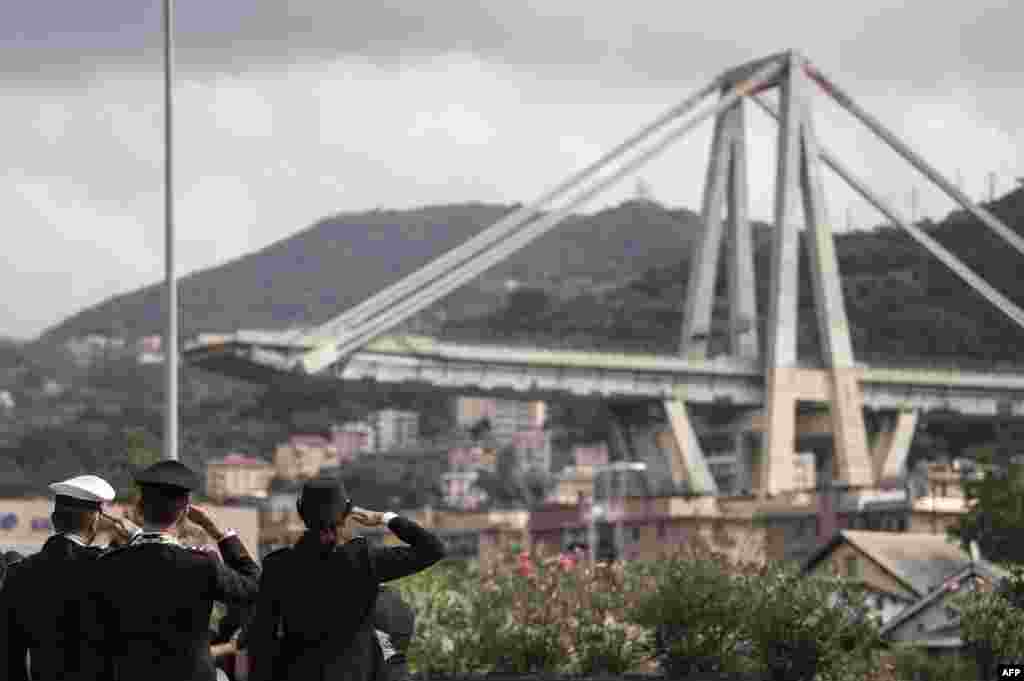 Member of the Italian Police pay tribute to the victims during a minute of silence and a commemoration ceremony near the bridge's wreckage, one month after the Morandi Bridge collapse that killed 43 people in Genoa.