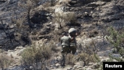 Personel militer membawa puing-puing menuruni lereng yang dihantam misil di Tashkent, di utara Siprus, 1 Juli 2019. (Foto: Yannis Kourtoglou)