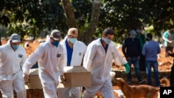 20일 브라질 상파울로의 묘지에서 장례업체 직원들이 신종 코로나바이러스 감염증(COVID-19) 사망자의 관을 운구하고 있다. 